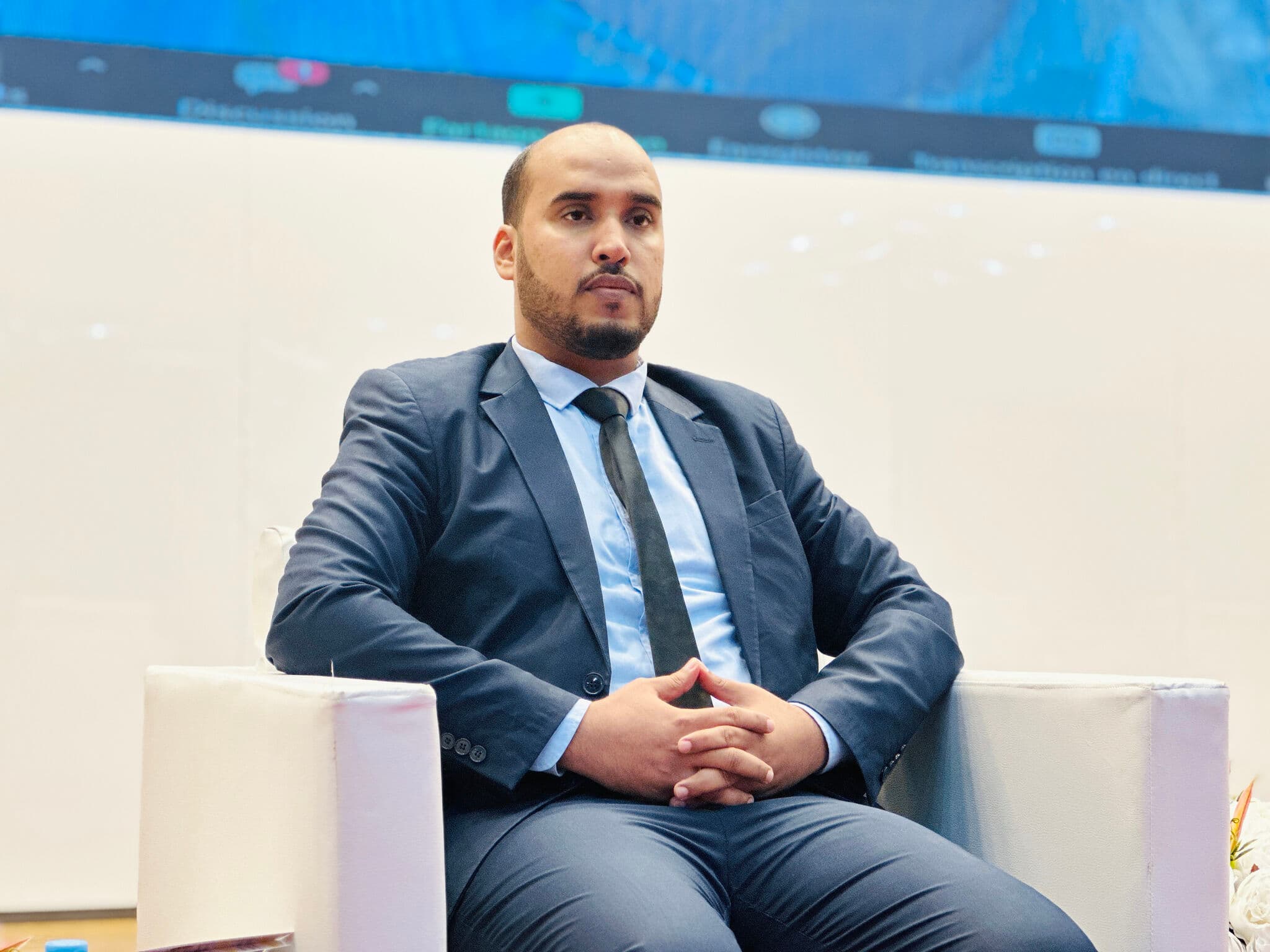 Portrait of Moustapha Cheikh seated during a conference panel